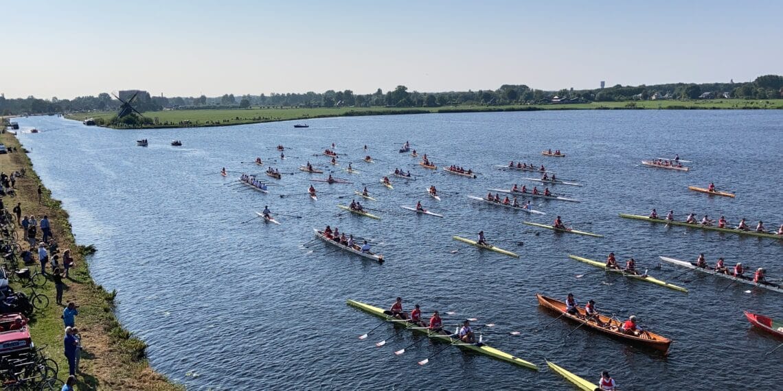 Vloot van jubilerende roeivereniging uit Heemstede voor groepsfoto op Molenplas